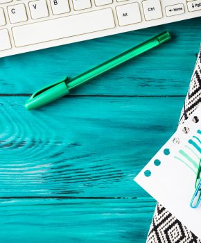 Workplace background with keayboard, notebook and coffee on dark green wooden background. Online blog concept